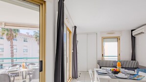 Quarto de hotel moderno com varanda, área de refeições e sofá.