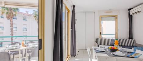 Moderni hotellihuone, jossa on parveke, ruokailutila ja sohva.