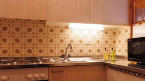 A kitchen with wooden cabinets, a stainless steel sink, an oven, and a microwave.