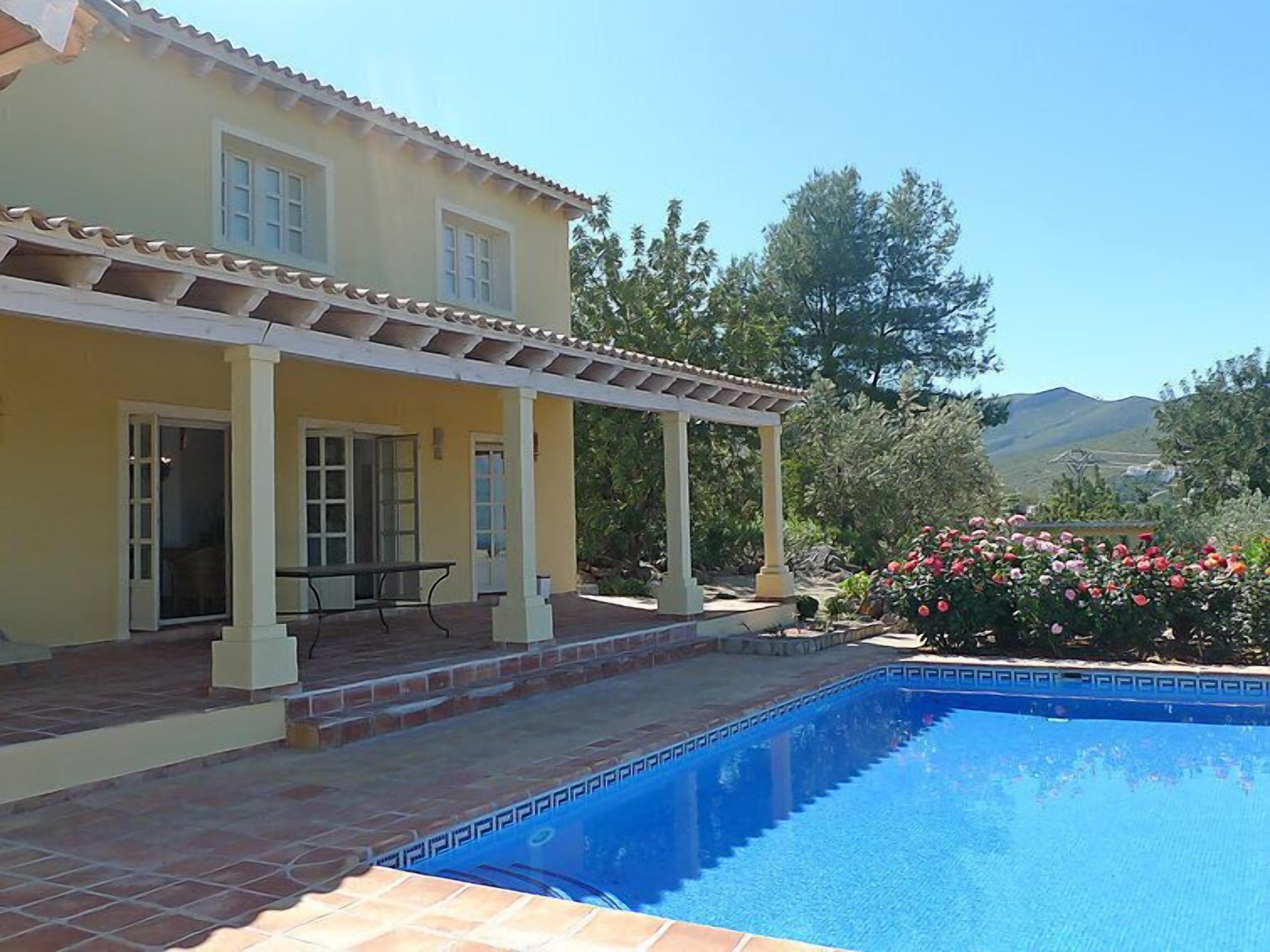 A two-story house with a covered patio and a swimming pool.