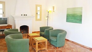 Un soggiorno con poltrone verdi, un camino, una televisione e un quadro appeso al muro.