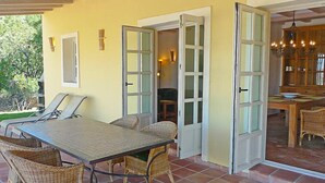 Un soggiorno open space con tavolo da pranzo, sedie in vimini e vista sulla cucina.