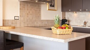 A modern kitchen with a central island, a stainless steel range hood, and a tiled backsplash. - Olympic R4 by Interhome (Nendaz)