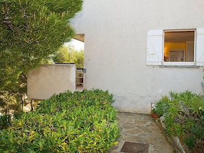 A narrow stone pathway leading to a white building with a window.