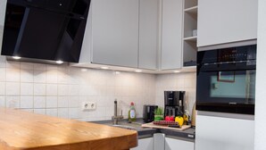 Eine moderne Küche mit weißen Schränken, einer Holzausziehtheke und einem eingebauten Backofen.