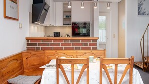 Eine kompakte Küche mit Backstein-Spritzschutz, einem eingebauten Backofen und einem Essbereich mit Holzküchenmöbeln und einer Bank.
