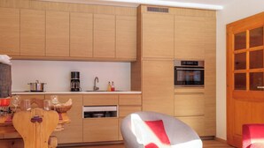 A modern kitchen with wooden cabinets, a built-in oven, and a coffee maker. - Ecluses 2 by Interhome (Nendaz)