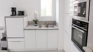 A modern kitchen with white cabinetry, a built-in oven, and a coffee maker on the countertop. - Le Méditerranée by Interhome (Fréjus)