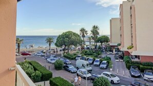 A hotel parking lot with cars, a beach view, and palm trees. - Le Méditerranée by Interhome (Fréjus)