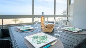 Taula de dinar preparada amb plats, coberts i gots, amb una ampolla i una cistella de pa damunt la taula.