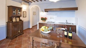 Une cuisine avec un îlot central en bois, un four encastré et un évier. On peut voir des bouteilles de vin et des verres sur l’îlot.