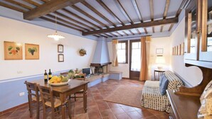 Une pièce spacieuse avec un plafond en bois, une table à manger avec des chaises, un canapé et une cheminée.