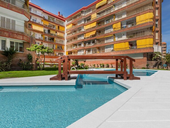 Ein mehrstöckiges Hotel mit Schwimmbad, Balkonen und einer roten Backsteinfassade.