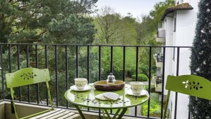 A balcony with a round table, two chairs, and a small garden view. - Demeures de Maignon by Interhome (Anglet)