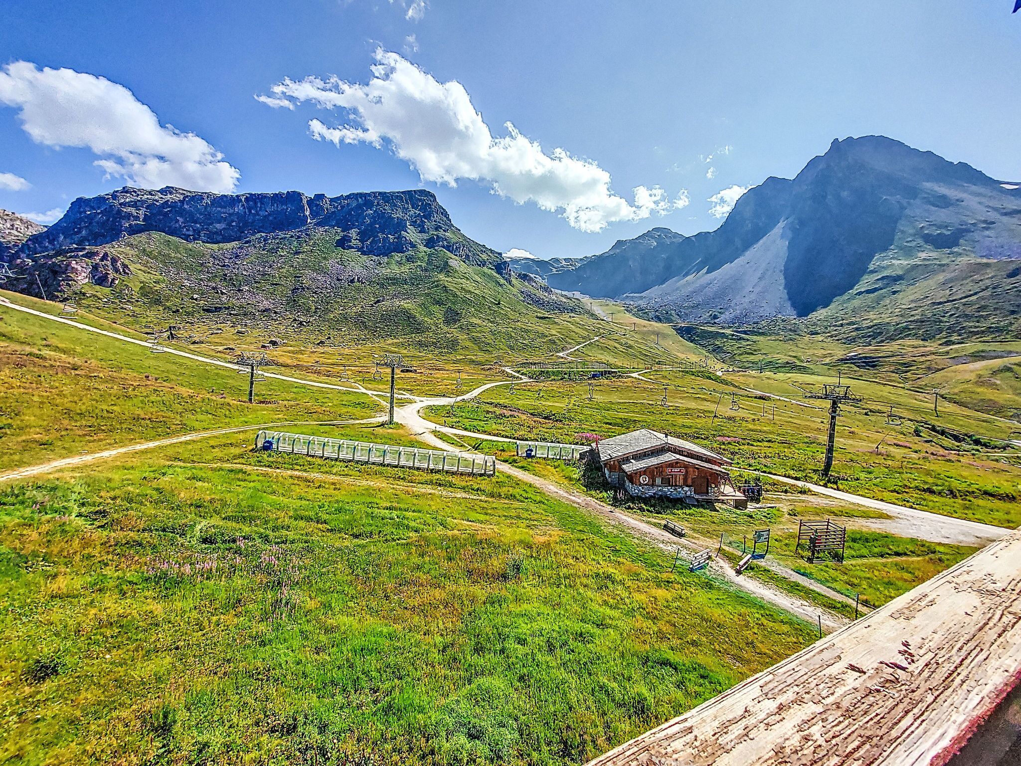 Un paysage montagneux avec un petit bâtiment, une voie ferrée et un télésiège.