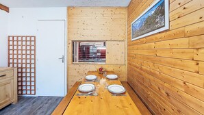 Ein Zimmer mit Holzwandverkleidung, einem Esstisch für vier Personen, einem Fenster mit Aussicht und einer Tür.