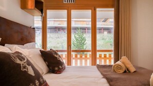 Ein Hotelzimmer mit Bett, Kissen, Decke und Blick auf den Balkon.