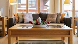 Ein modernes Wohnzimmer mit einer Holzdirektiva, einem Glastisch und einer Kerzenarragement.