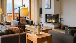 Ein modernes Wohnzimmer mit Kamin, bequemen Sitzmöglichkeiten und einem großen Fenster mit Blick ins Freie.
