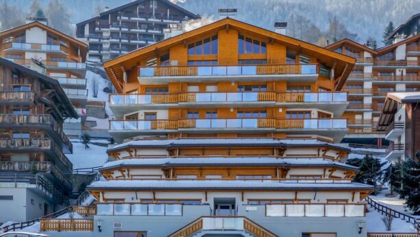 Ein mehrstöckiges Holzgebäude mit Balkonen, umgeben von Schnee.