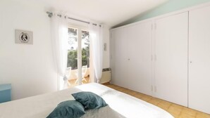 A bedroom with a bed, a wardrobe, and a balcony.