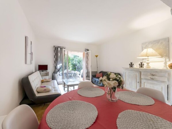 A dining area with a red table, white chairs, and a vase with flowers.