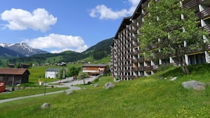 Un hôtel moderne avec une vue imprenable sur les montagnes, agrémenté d’un arbre remarquable et d’un ciel dégagé.