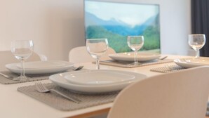 Una mesa de comedor dispuesta con platos, vasos y cubiertos, con un cuadro de paisaje al fondo.