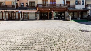 A hotel entrance with a cobblestone plaza, multiple balconies, and a sign for a souvenir shop. - Rond Point des Pistes (Val Claret) by Interhome (Tignes)