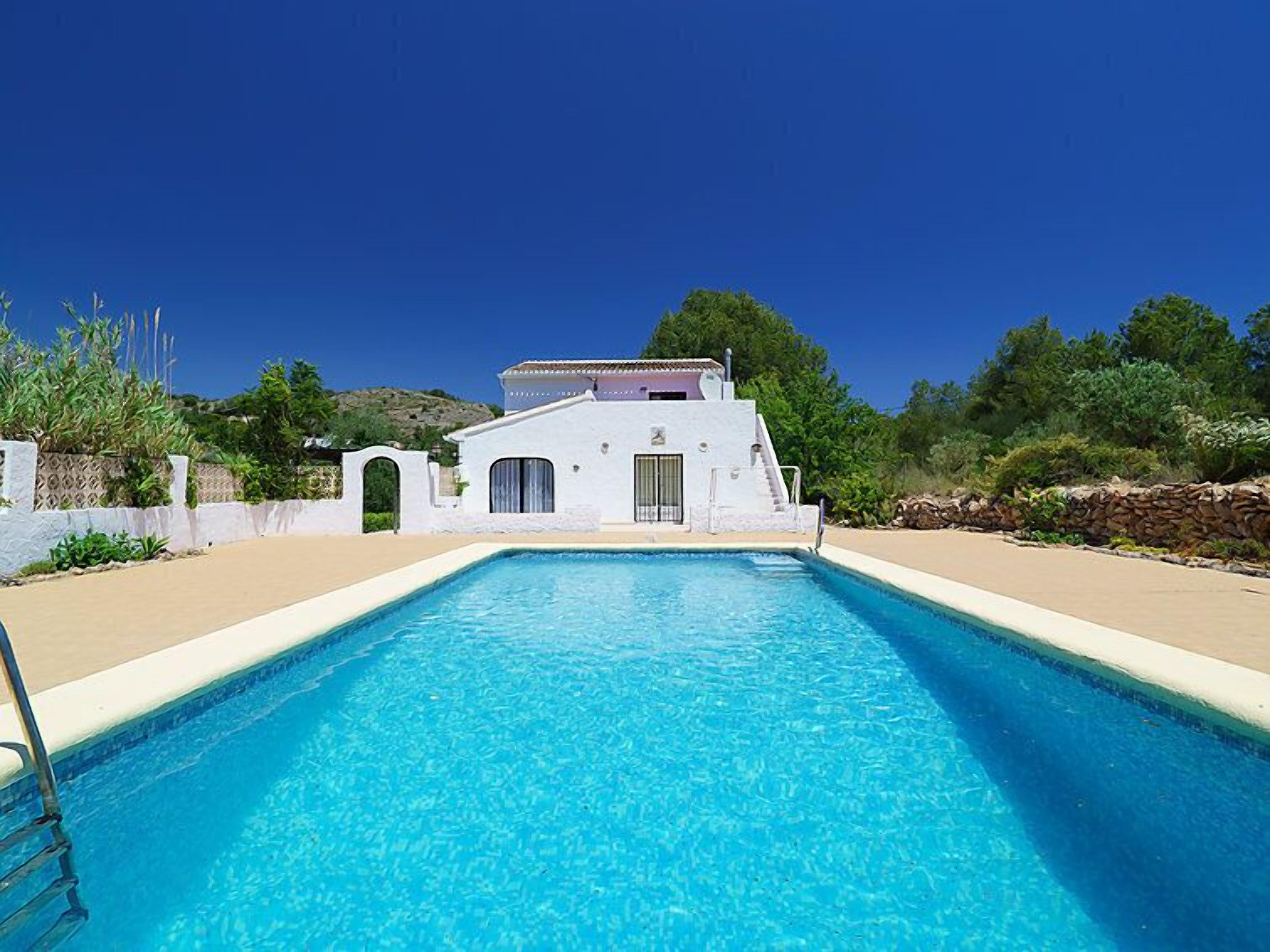Piscina com um edifício branco ao fundo.