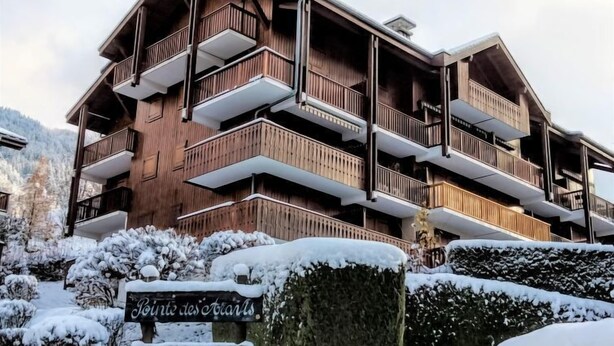 Un edificio de madera de varios pisos con balcones, un letrero que indica propiedad privada y alrededores cubiertos de nieve.
