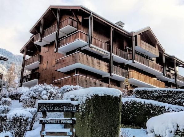A multi-story wooden building with balconies, a sign indicating private property, and snow-covered surroundings.