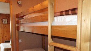 Habitación con literas de madera y ropa de cama blanca.