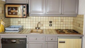 Una cocina con gabinetes grises, un microondas, un fregadero, una estufa y un lavavajillas.