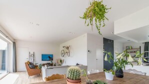 Un salon moderne avec une table à manger en bois, des plantes en pot et un téléviseur.