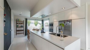 Une cuisine moderne avec des meubles blancs, un îlot central et un four encastré.