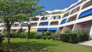 A modern hotel with multiple balconies, a well-maintained lawn, and a clear blue sky.