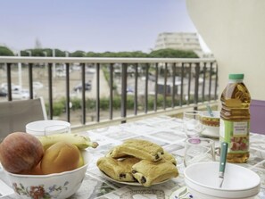 A balcony table with a bowl of fruit, a bottle of oil, and a plate of pastries. - Les Jardins du Port by Interhome (Port Camargue)