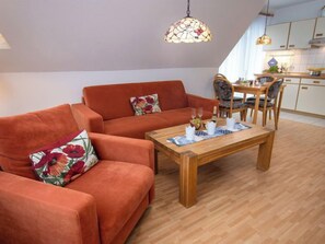 Una sala de estar acogedora con sofá y una mesa de centro, un comedor con sillas y una cocina al fondo.