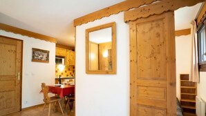 A wooden interior with a dining area, a mirror, and a staircase. - Balcons d'Olympie 204 - A by Interhome (Les Menuires)