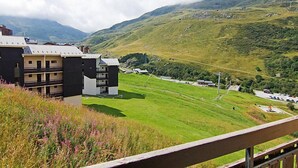 Een modern gebouw met meerdere balkons met uitzicht op een groene vallei en bergen.