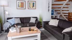 En moderne stue med en mørkebrun sofa, et træbord og to indrammede abstrakte malerier på væggen.