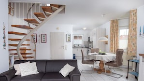 En moderne stue med en mørkegrå sofa, et træsofabord og en trappe med sving.'