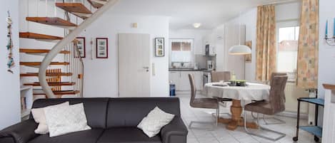 Ett modernt vardagsrum med en mörkgrå soffa, ett träbord och en spiraltrappa.
