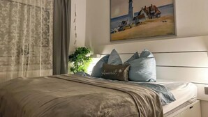 A bedroom with a bed, a painting of a lighthouse, and a plant. - Muschelweg by Interhome (Norddeich)