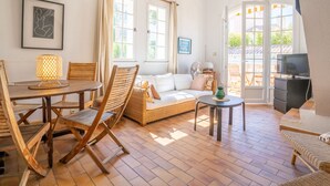 Un salon chaleureux avec une table à manger en bois, des chaises en osier, un canapé et un téléviseur.