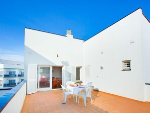 A white building with a tiled patio, a pool, and a table with chairs. - Platja de Roses by Interhome (Roses)