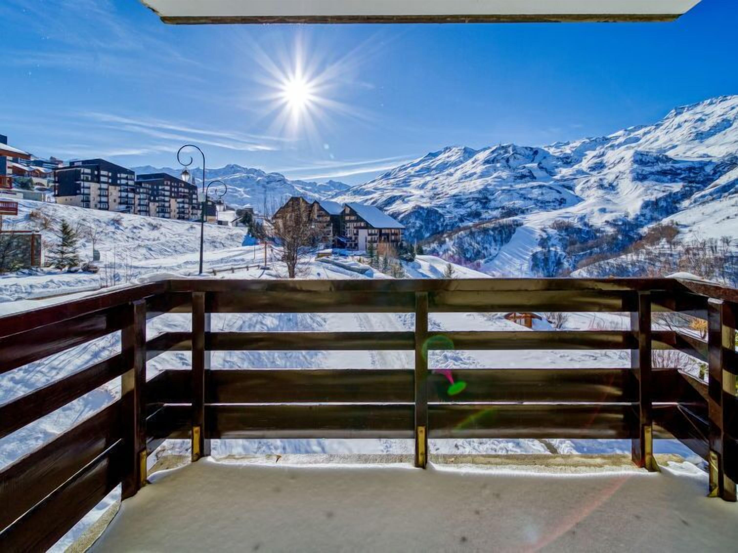 A wooden bench overlooking a snowy mountain landscape with buildings in the background.