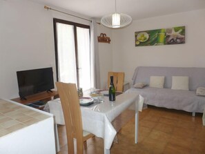 Un salon avec un téléviseur, une table à manger et un canapé.