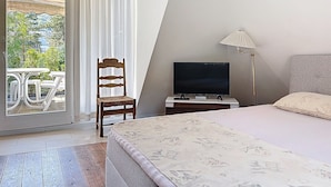Een slaapkamer met een bed, een televisie, een stoel en een tafel naast een glazen schuifdeur.
